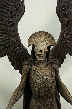 a statue of an alien with wings and eyes on it's head, standing in front of a white background