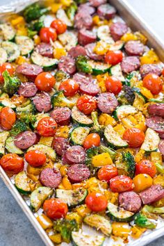 a pan filled with sausage, tomatoes and zucchini