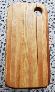 a wooden cutting board sitting on top of a carpeted floor with a hole in the middle