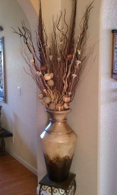 a vase with dried flowers in it sitting on a shelf