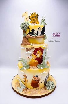 a three tiered cake decorated with the lion king and jungle princesses on it