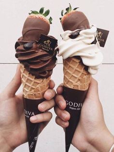 two people holding ice cream cones in their hands