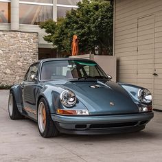 a blue porsche parked in front of a building