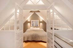 an attic bedroom with white walls and wood flooring is lit by recessed lights