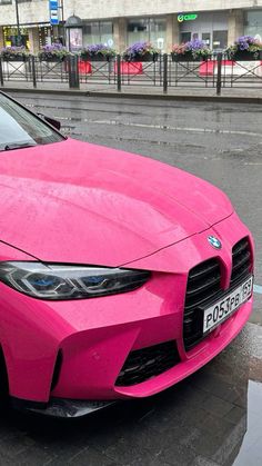 a pink sports car parked on the side of the road in front of a building