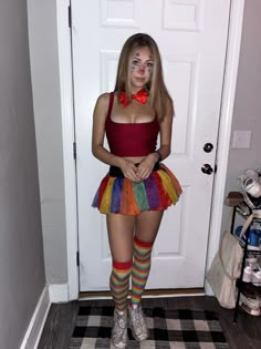 a woman with makeup on her face standing in front of a door wearing a rainbow skirt and bow tie