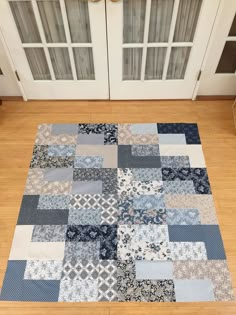 a blue and gray patchwork rug on the floor in front of two white doors