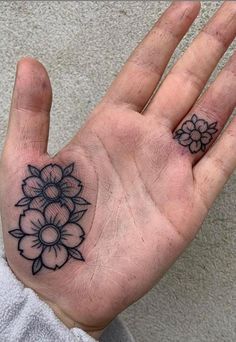 a person's hand with a flower tattoo on the middle of their left palm