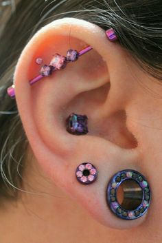 the ear is decorated with colorful beads and pink flowers on it's side, as well as a pair of piercings