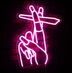 a neon sign that is on the side of a brick wall with a hand holding a crucifix