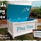 a blue and white toy box sitting on top of a grass covered field next to a brick wall