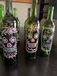 three green bottles with skulls painted on them sitting on a table next to each other