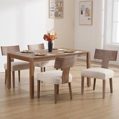 a dining room table with chairs and a vase filled with flowers on top of it