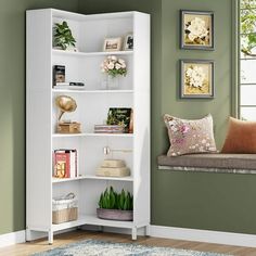 a white book shelf in a room with green walls and flowers on the window sill