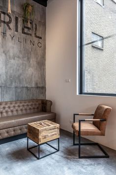 a living room filled with furniture next to a large window and a painting on the wall