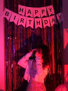 a woman standing in front of a birthday banner