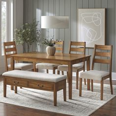 a dining room table and chairs with a bench in front of it on a rug