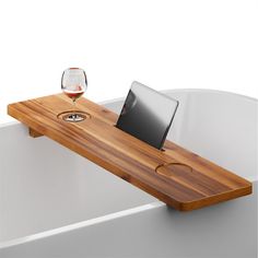 a wooden table with a laptop on it and a glass of wine in the background