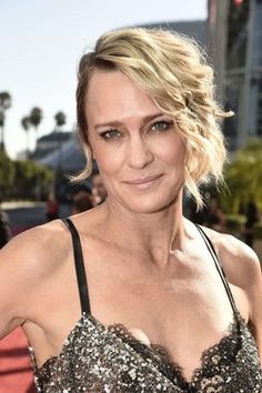 a woman with blonde hair wearing a black and silver dress on the red carpet at an event