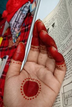 a person's hand with red paint on it and a book in the background