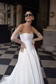 a woman in a white wedding dress posing for the camera with her hands on her hips