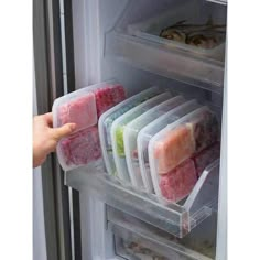 the refrigerator door is open and there are many different foods in plastic containers on it