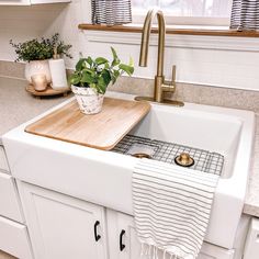 a kitchen sink with a cutting board on the bottom and a towel hanging over it