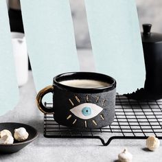 there is a coffee cup with an eye on it next to some marshmallows