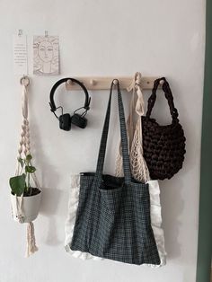 three purses hanging up on a wall with hooks and string attached to it's sides