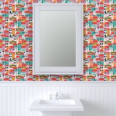 a bathroom sink sitting under a mirror next to a wall mounted faucet in front of a colorful tiled wall