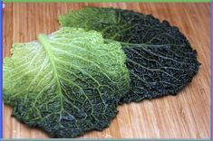 two green leafy vegetables sitting on top of a wooden cutting board