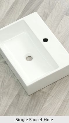 a white square sink sitting on top of a wooden floor next to a faucet hole