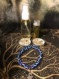 a blue beaded bracelet and bottle of oil sit on a black tablecloth with gold designs