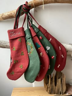 five christmas stockings hanging from a tree branch