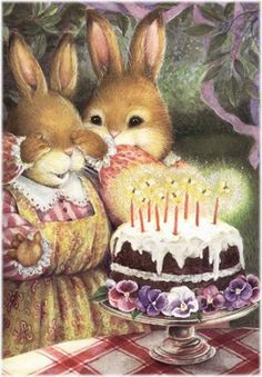 two rabbits sitting next to a cake with candles on it and one bunny holding the rabbit's head