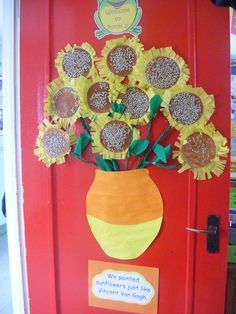 a vase filled with sunflowers sitting on top of a red door next to a sign