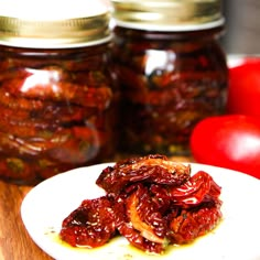 a plate with some food on it and two jars full of tomatoes in the background