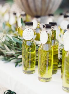 olive oil bottles are lined up on a table with rosemary sprigs and tags