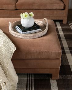 a living room with a couch, ottoman and book on the coffee table in front of it