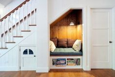 a dog house built into the side of a stair case in a home with wood floors and white walls