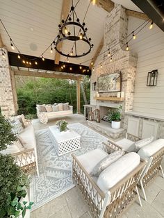 an outdoor living area with white furniture and string lights