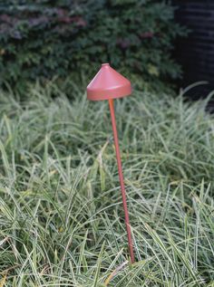 a pink lamp sitting in the middle of some tall grass