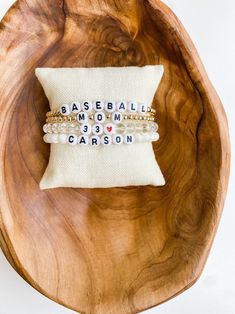 two bracelets sitting on top of a wooden bowl next to a pillow with words written on it