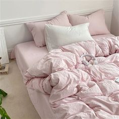 an unmade bed with pink sheets and headphones on the bottom shelf next to it