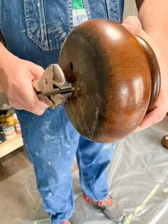 a person holding a large wooden object in their hand and working on it's side