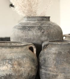 several old pots are stacked on top of each other and one has a plant in it