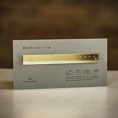 a business card with a gold bar on it sitting on a white table next to a brown wall