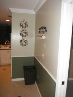 the corner of a kitchen with green and white paint on the walls, and a black trash can next to it