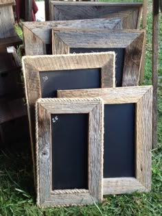 four wooden frames sitting in the grass with chalkboards attached to them and one is empty