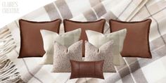 four pillows and two throw pillows on a plaid blanket with fringes in the background